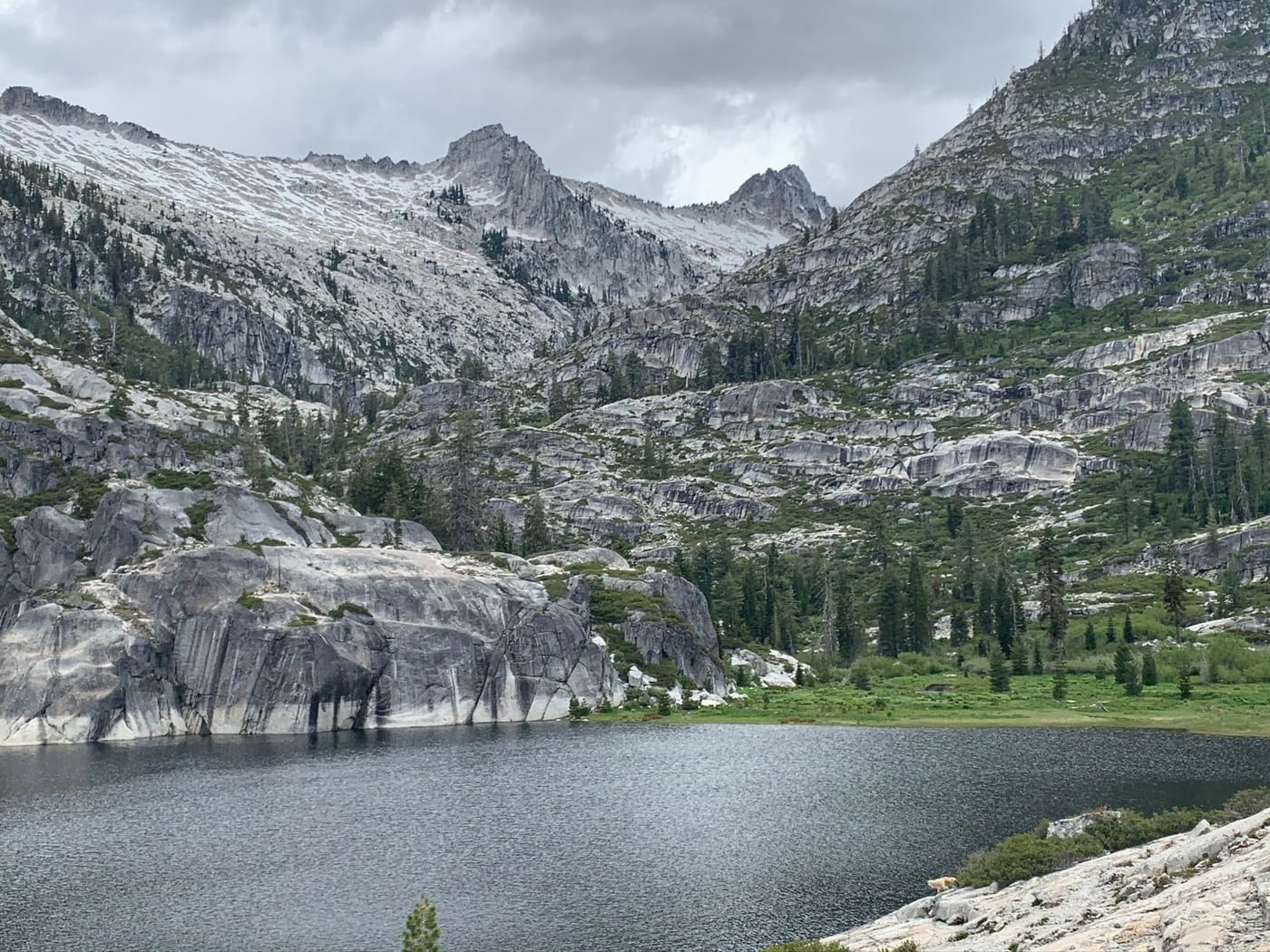 Snow-dusted granite peaks above a still alpine lake.