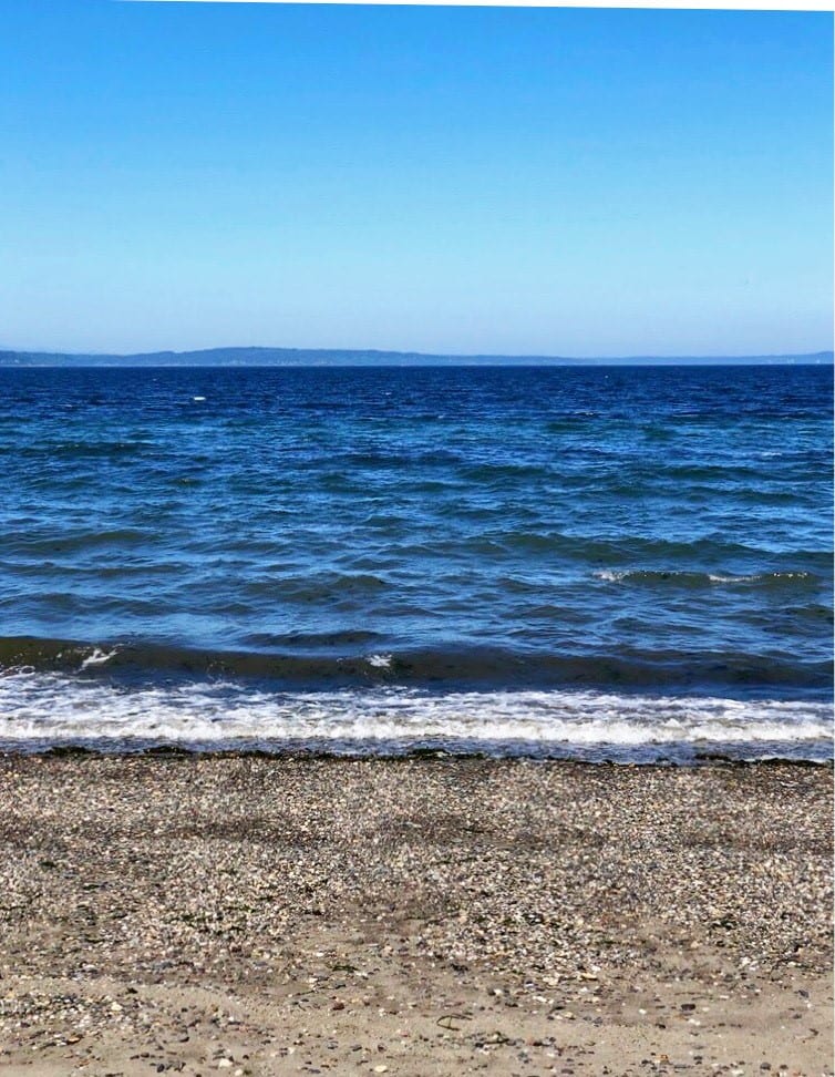 Deep blue water breaking on a pebble shore.