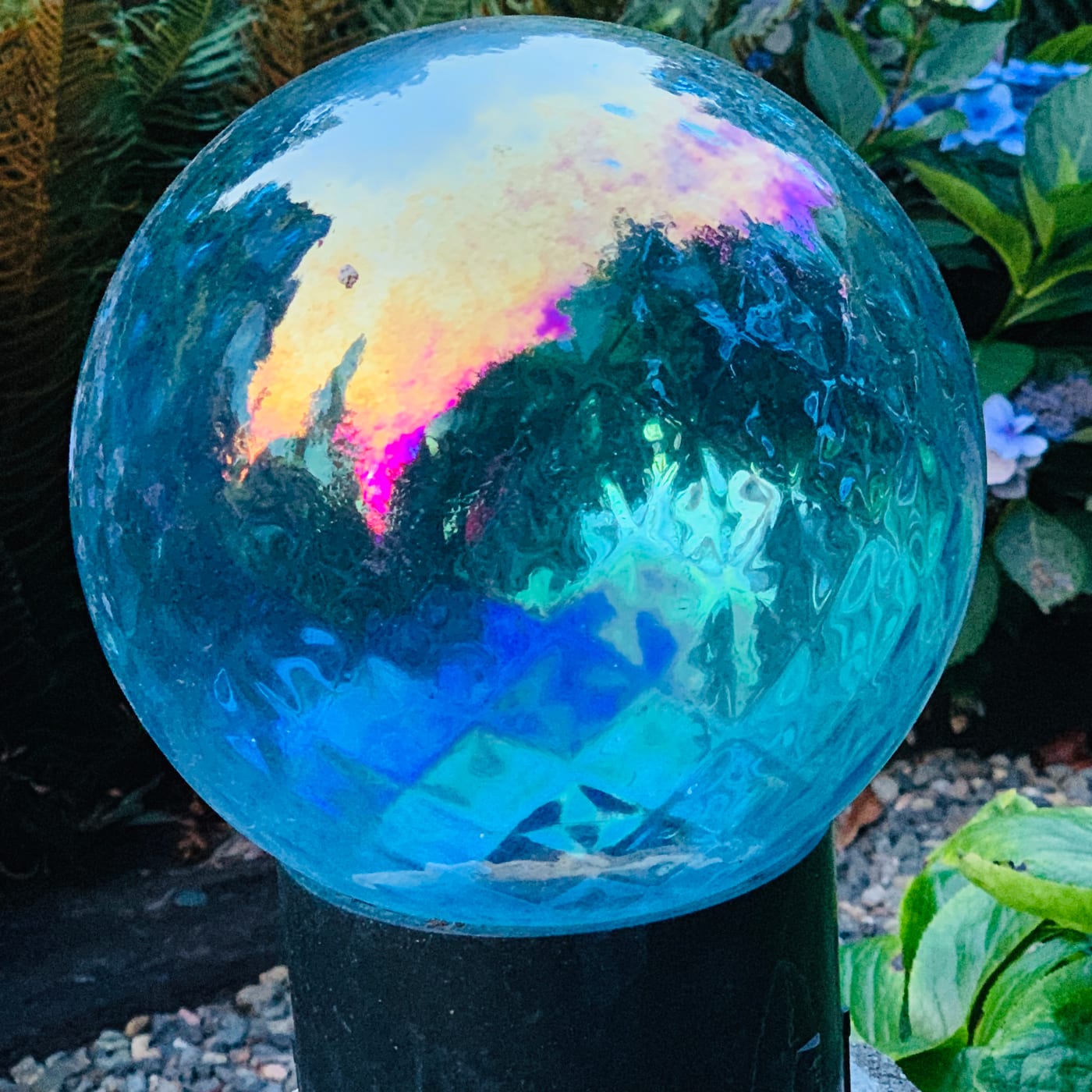 Iridescent glass sphere reflecting a garden.