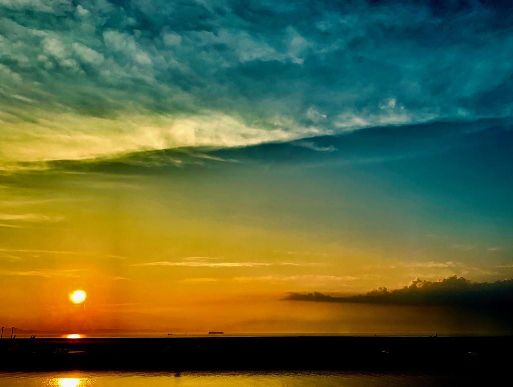 Bands of teal, gold, and orange sunset sky over the sea.