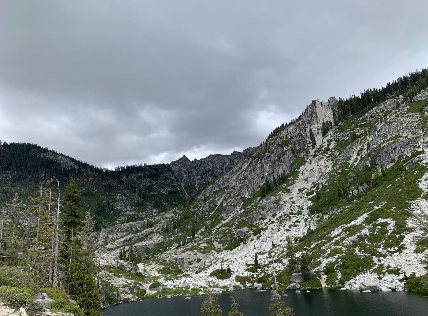 Evergreen slope rising above a granite basin.