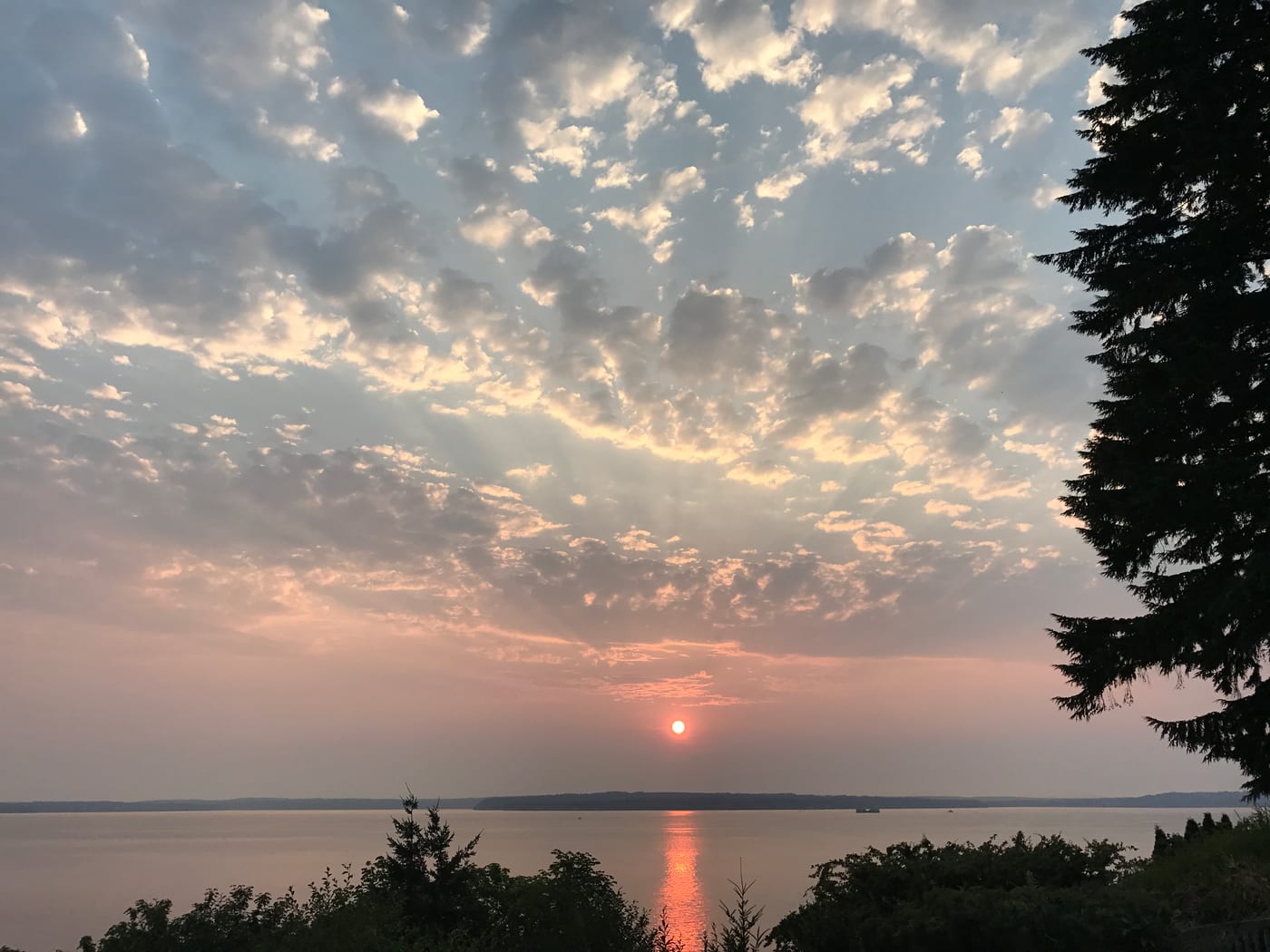 Hazy red sun setting over the water.