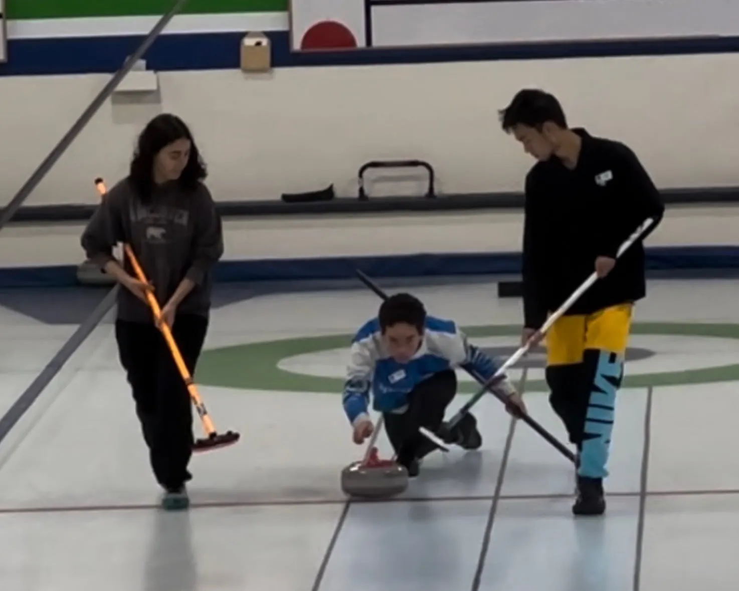 Kellan releasing a curling stone mid-delivery.