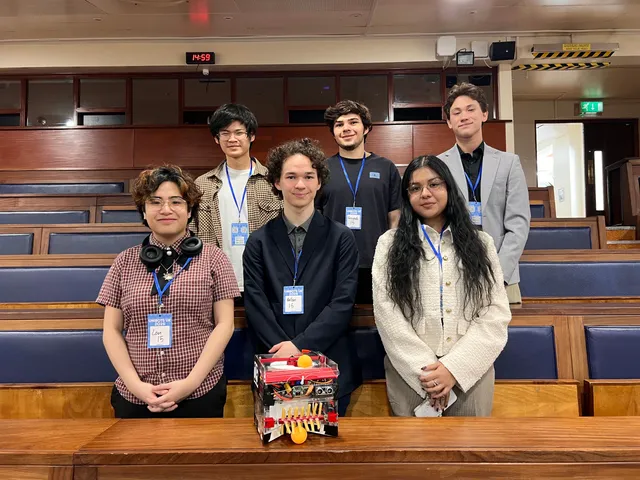 Six team members standing behind their competition robot in the lecture hall at Unibots UK 2026.